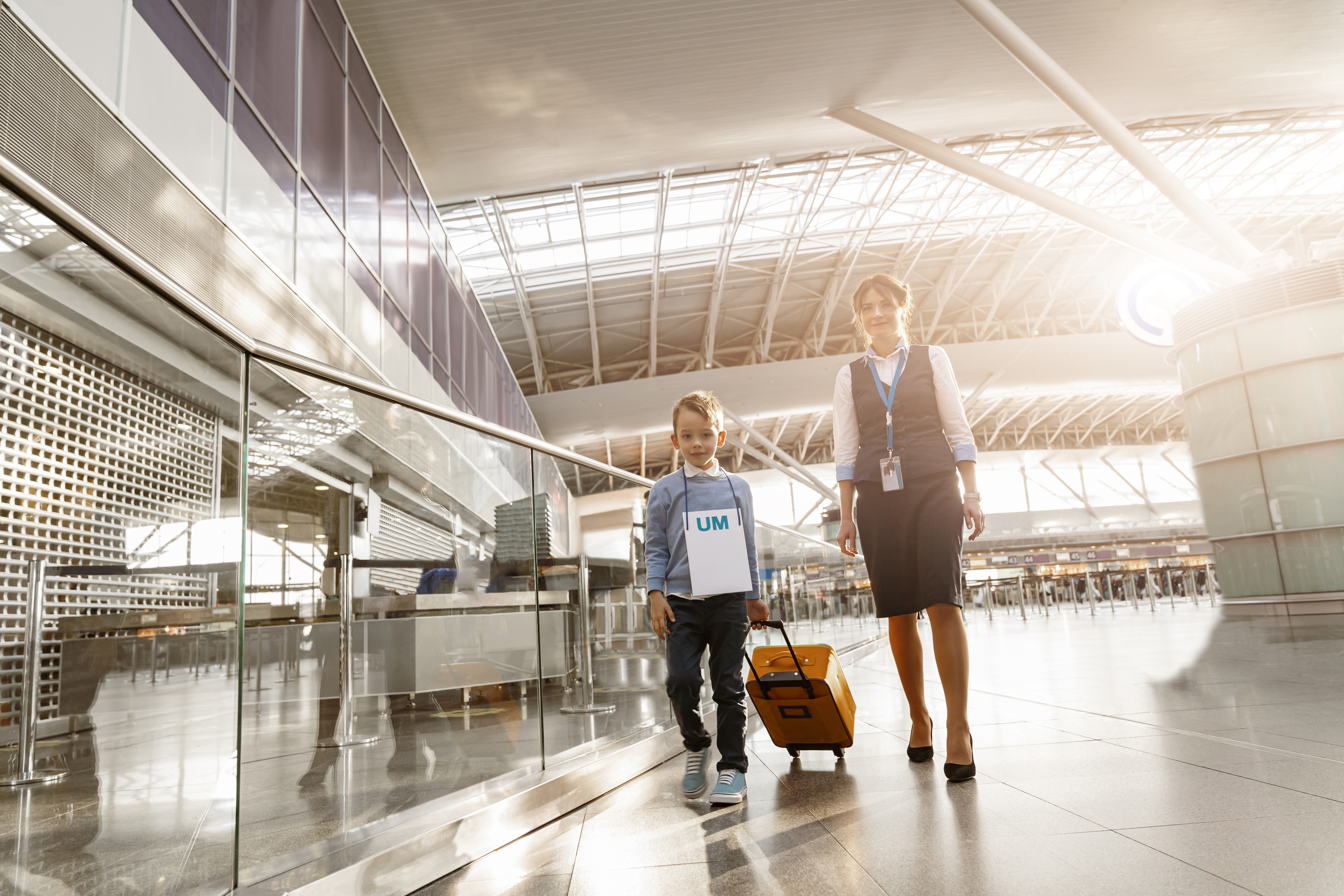 Female airport worker helps a little boy to find correct gate for boarding at the airport