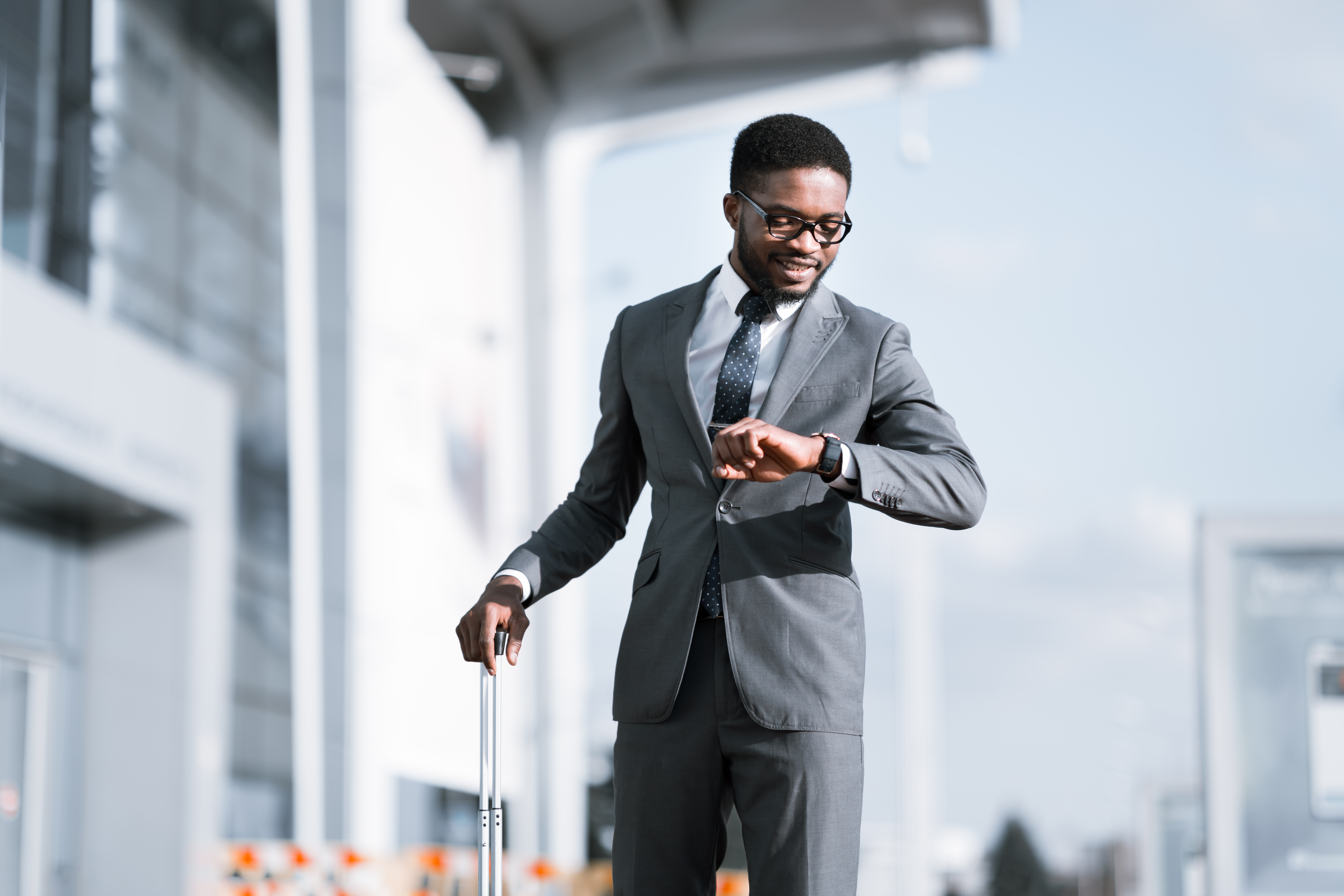 Businessman Smiling Looking At Wristwatch Arriving At Airport In Time